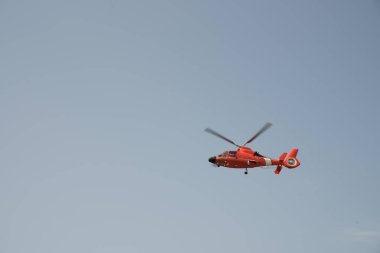Bulutsuz gökyüzünde uçan turuncu helikopter