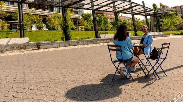 Madre e hija sentadas en la mesa del café con el parque en la parte trasera — Foto de Stock