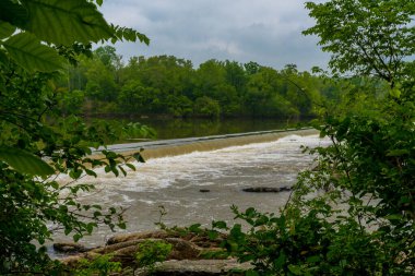 Nehirdeki barajın üzerinden akan küçük şelale gibi.