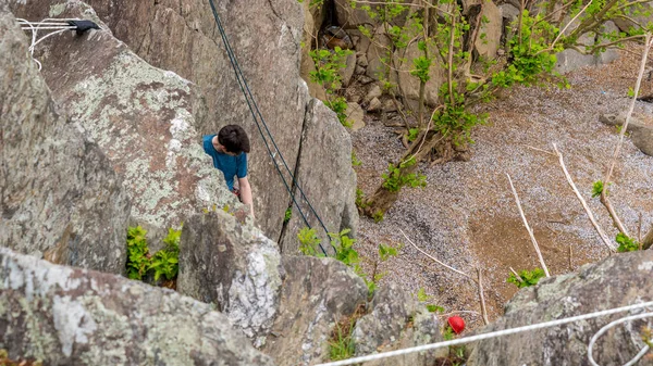 Hombre escalando rocas y mirando al escalador de abajo — Foto de Stock