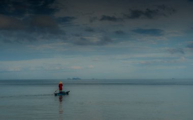 Yaşlı adam Tayland Körfezi 'ndeki sakin denizlerde smal geleneksel teknede balık tutuyor.