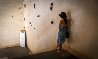 Bologna İtalya 'daki eski bir binada siyah şapkalı ve mavi güneş elbiseli bir kadın duvara yaslanıyor.