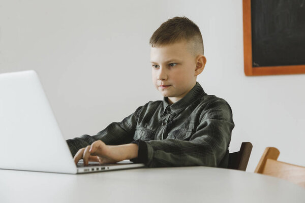Little dependent gamer boy playing on laptop indoors - Image