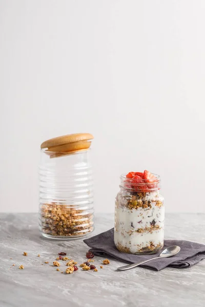 Granola och yoghurt och frukter på topping i glas på stenbord — Stockfoto