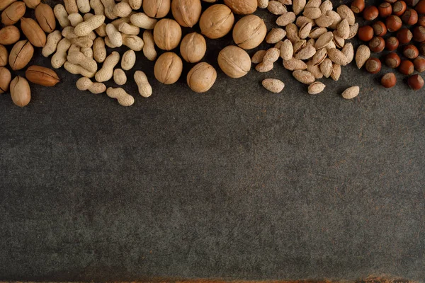 Рама из различных видов орехов на каменном фоне — стоковое фото