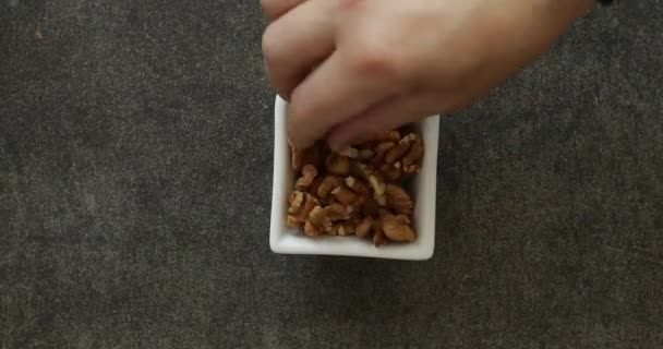 Mannelijke hand plukken walnoot uit witte vierkante kom close-up. Gezond voedselconcept — Stockvideo
