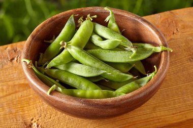 Ahşap arka plan üzerinde bezelye bakla ile kase havai görünümü