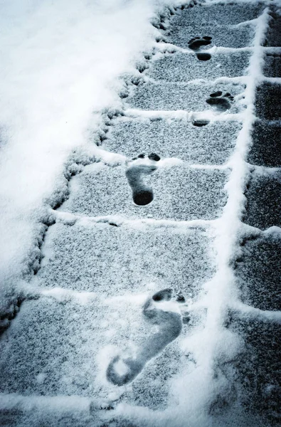 seasonal background footprints feet on the snowy sidewalk