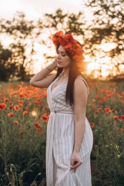 Gün batımında haşhaş tarlasında güzel bir esmer kızın portresi.