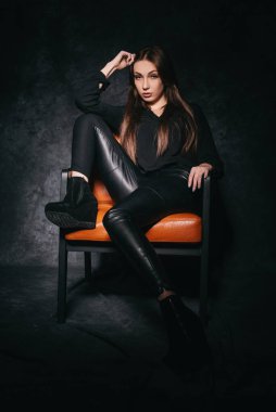 Stüdyoda güzel bir esmer, bir fotoğraf stüdyosunun karanlık arka planında.