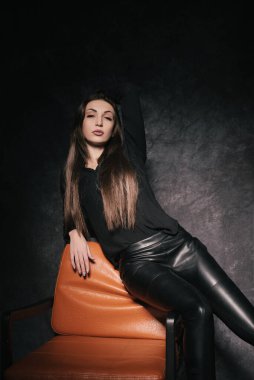 Stüdyoda güzel bir esmer, bir fotoğraf stüdyosunun karanlık arka planında.