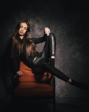 Stüdyoda güzel bir esmer, bir fotoğraf stüdyosunun karanlık arka planında.