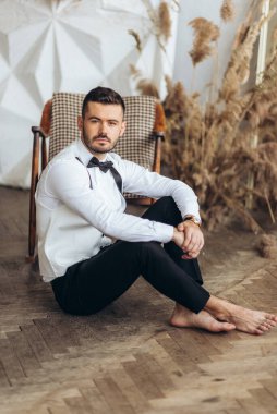 Aynanın yanındaki evde yakışıklı damat. Genç damat hazırlanıyor. Nişanlısı sabah evde. Düğünden önce damat hazırlığı.