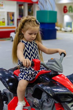 Mutlu çocuklar, küçük kız çocuk yolda kırmızı büyük bir arabaya biniyor. Kapatın. Bebek arabayı sürüyor ve bir doğum günü partisinde bir çocuk oyun odasında oynuyor. Eğlence merkezinde vakit geçiriyoruz..
