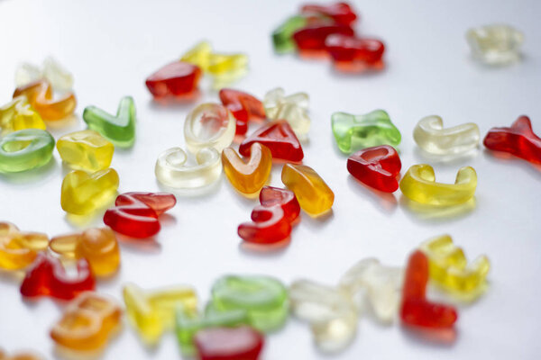 Shiny gummy alphabet letters on white background