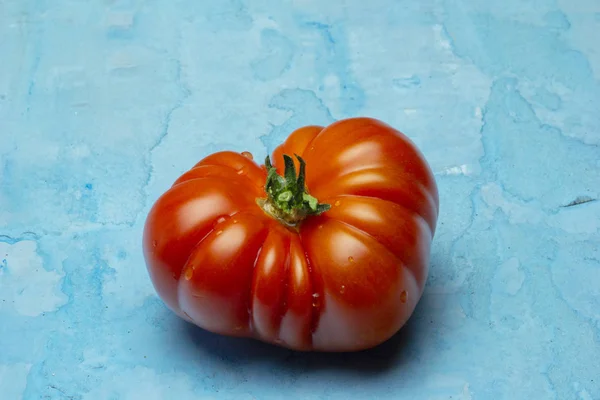 Beautiful Brandywine red tomatoes, in heart shape on grunge blue background