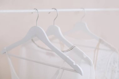 Beyaz bir askı elbise. Minimalizm kavramı. Düğün kadınlar kümesi bir ahşap askı, moda arka plan elbise, yakın çekim