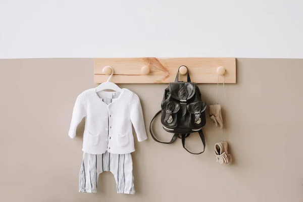 Detalles interiores de la habitación de los niños sobre fondo claro. Percha de madera decorativa con bolso y traje de punto para niños en pared blanca y marrón — Foto de Stock