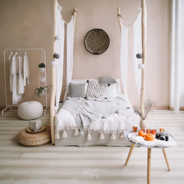 Moderne huis interieur. Bed met houten luifel en kussens, deken en een nachtkastje met kaarsen. Exotische slaapkamer interieur, Scandinavische stijl — Stockfoto