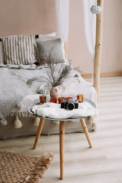 Modern home interior design. Bed with wooden canopy and pillows, blanket and a bedside table with retro camera and candles. Exotic bedroom interior, scandinavian style — Stock Photo, Image