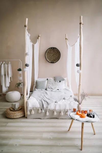 Nowoczesna aranżacja wnętrz. Łóżko drewniane zadaszenie i poduszki, koc i stolik ze świecami. Egzotycznych sypialni wnętrze, skandynawski styl — Zdjęcie stockowe
