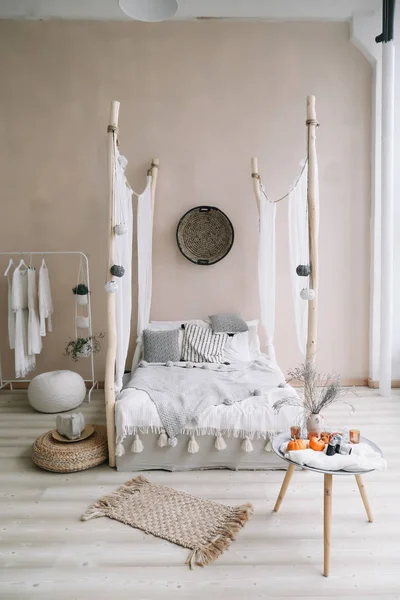 Moderne huis interieur. Bed met houten luifel en kussens, deken en een nachtkastje met kaarsen. Exotische slaapkamer interieur, Scandinavische stijl — Stockfoto