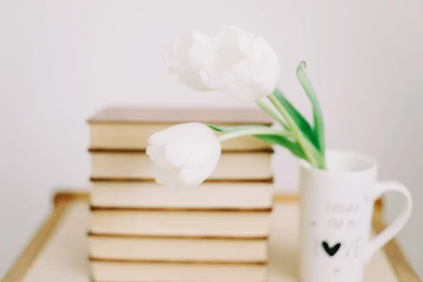 Kytici krásných bílých tulipánů. Čerstvé jarní květiny a knihy na bílém pozadí. — Stock fotografie