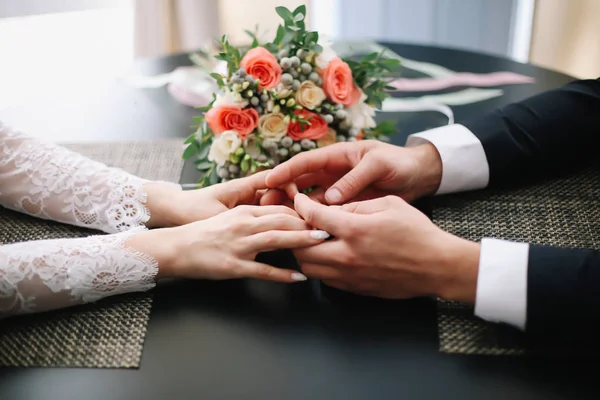 Handen van bruid en bruidegom met ringen en een mooie bruiloft boeket — Stockfoto