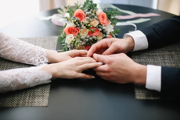 Handen van bruid en bruidegom met ringen en een mooie bruiloft boeket — Stockfoto