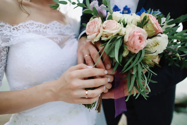 Bruid en bruidegom houden een bruiloft boeket, trouwjurk, wedding details — Stockfoto