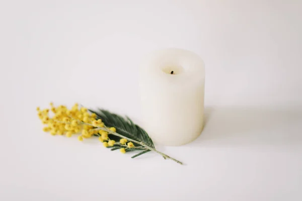 White candle with a flower  on a white background. Easter, spring, holiday concept. Flat lay, top view
