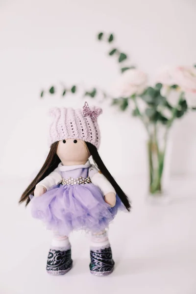 A handmade doll with long brown hair in beautiful dress on white background. Decorative doll. Clothes for handmade dolls.