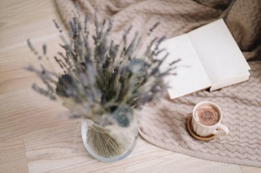 ahşap arka planda kitap ve fincan kahve ile lavanta buket. Kurutulmuş çiçekler ve kitap ile bir fincan cappuccino, bahar konsepti. üst görünüm. yatık