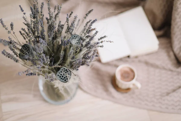 ahşap arka planda kitap ve fincan kahve ile lavanta buket. Kurutulmuş çiçekler ve kitap ile bir fincan cappuccino, bahar konsepti. üst görünüm. yatık