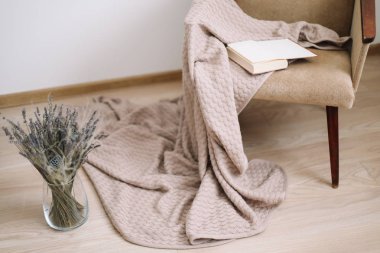 Rahat ev dekoru. bir battaniye ve bir kitap, bir buket lavanta ile bir vazo ile koltuk. Modern ev iç tasarım.
