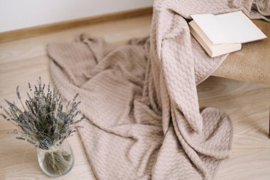 Rahat ev dekoru. bir battaniye ve bir kitap, bir buket lavanta ile bir vazo ile koltuk. Modern ev iç tasarım.
