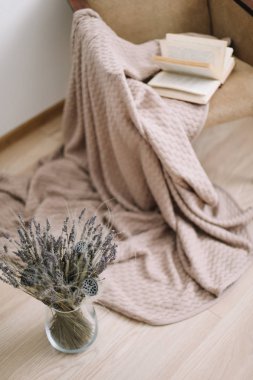 Rahat ev dekoru. bir battaniye ve bir kitap, bir buket lavanta ile bir vazo ile koltuk. Modern ev iç tasarım.