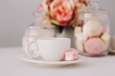 Beyaz arka planda şekerleme olan beyaz bardak. Romantik kahvaltı. Tatil kavramı, doğum günü, Paskalya. düz yat