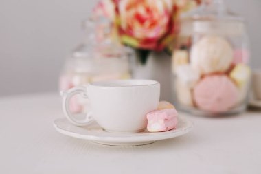 Beyaz arka planda şekerleme olan beyaz bardak. Romantik kahvaltı. Tatil kavramı, doğum günü, Paskalya. düz yat