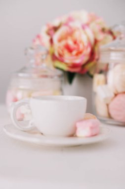 Beyaz arka planda şekerleme olan beyaz bardak. Romantik kahvaltı. Tatil kavramı, doğum günü, Paskalya. düz yat