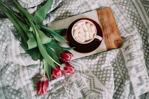 Xícara de café com marshmallows e tulipas vermelhas na cama. Conceito de feriado, aniversário, Páscoa, 8 de março. — Fotografia de Stock