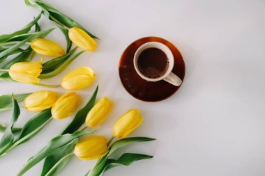 Beyaz arka planda lale ler çerçevesinde bir kahve fincanı. Düz yatıyordu, üstten bak. Tatil kavramı, doğum günü, Paskalya, 8 Mart