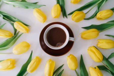 Beyaz arka planda lale ler çerçevesinde bir kahve fincanı. Düz yatıyordu, üstten bak. Tatil kavramı, doğum günü, Paskalya, 8 Mart