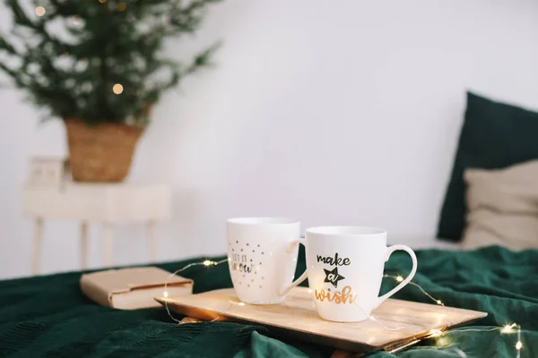 Accogliente camera da letto con tazze di caffè e libro a letto. Natura morta di Natale. Vacanze, Natale e Capodanno concetto — Foto Stock