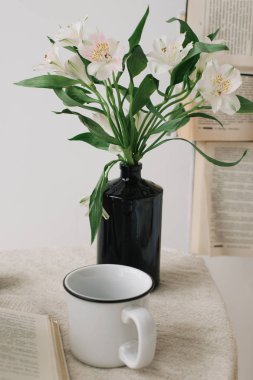 Bahar natürmortu. Yatakta kahvaltı. Beyaz yatak odası. Güzel bir ev. Kitaplar, çiçekler ve kahve fincanı. düz yatıyordu