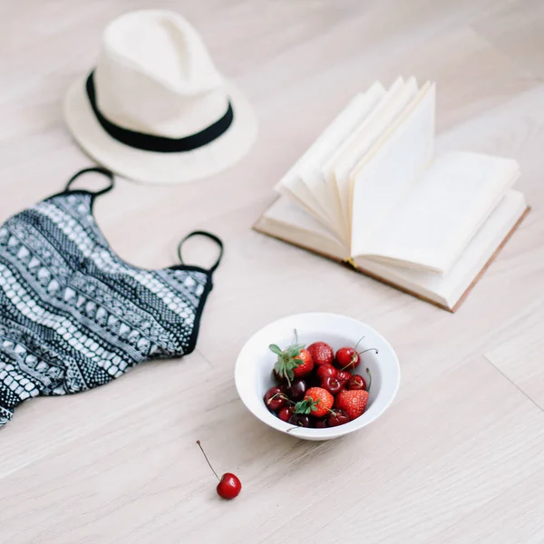 탑 뷰 여행 또는 휴가 개념. 수영복, 모자, 책과 나무 배경에 신선한 달콤한 체리와 딸기. 플랫레이. 여름 배경. — 스톡 사진