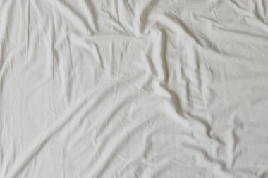 Beyaz kumaş doku arka plan. Kırışmış, kırışık kumaş. Gece uykusu sonrası dağınık yatak levha üst görünümü. Yumuşak odaklama