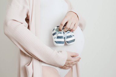 Annelerin elinde yeni doğan bebek booties. Hamile kadın göbek