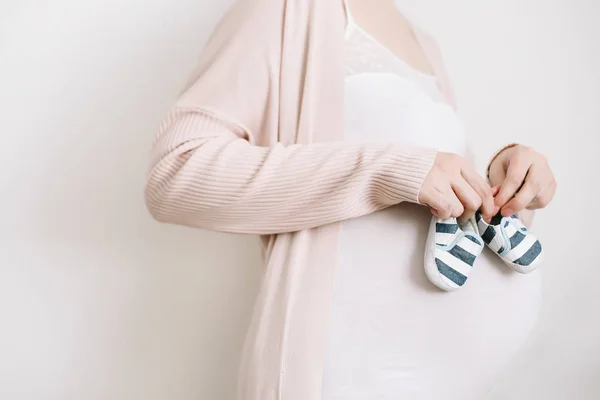 Booties w rękach przyszłej matki. Zbliżenie brzuch w ciąży — Zdjęcie stockowe