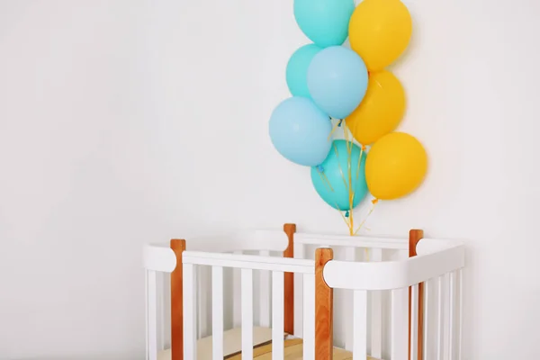 Interior del dormitorio de bebé. Interior minimalista de la habitación del bebé. Globos festivos frente a la cuna. Concepto de celebración de cumpleaños bebé . — Foto de Stock